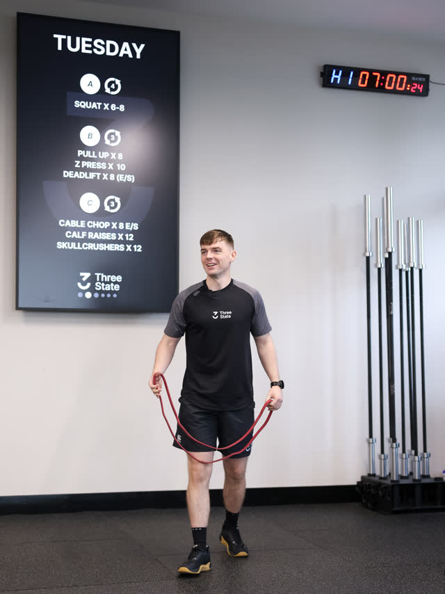 A smiling coach setting up the skipping ropes