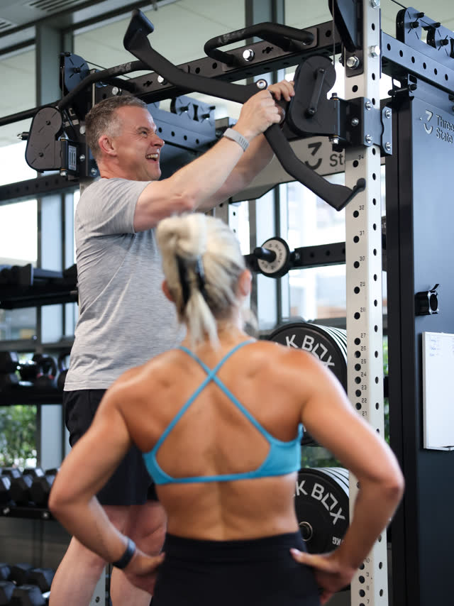 A coach guiding a member at the rack