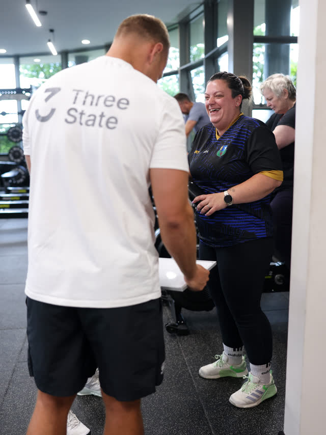 A coach helping a member set up, both smiling